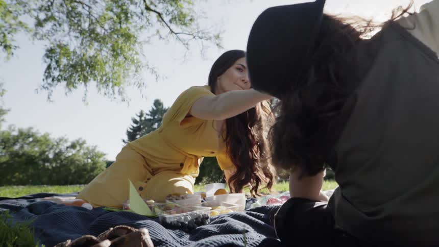A woman and child picnic on a grassy lawn