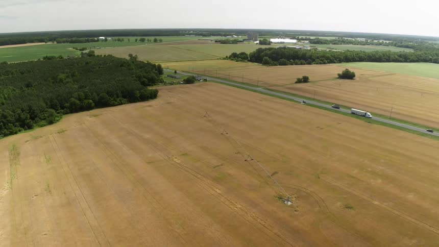 Vehicles travel down the highway next to a field