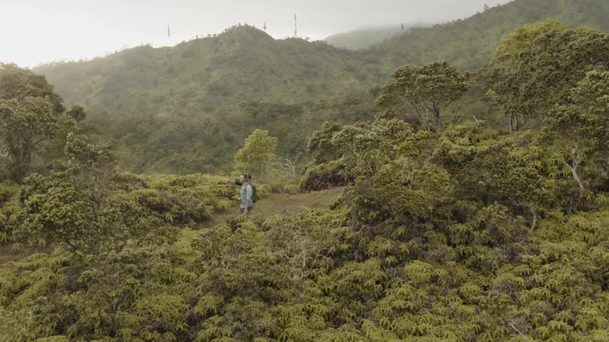 Two men walk over tree covered hills