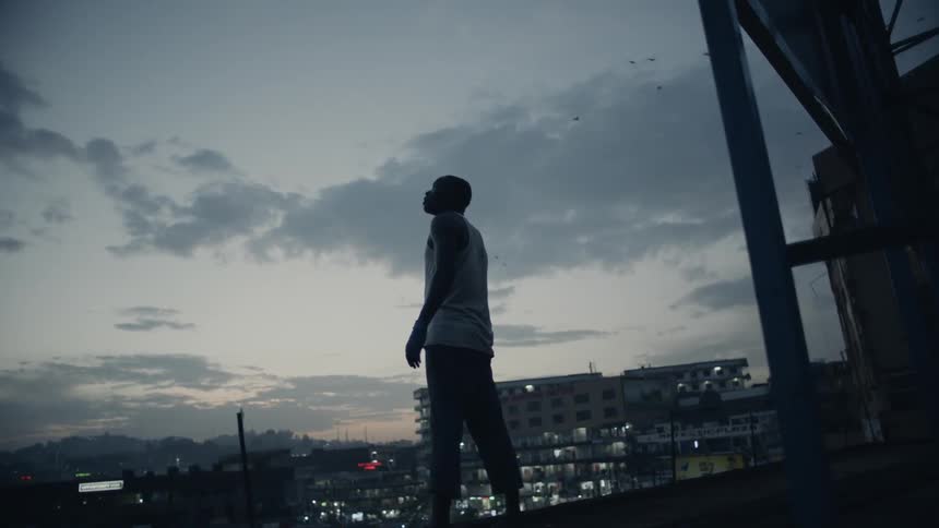 A man stands on a building rooftop at dusk