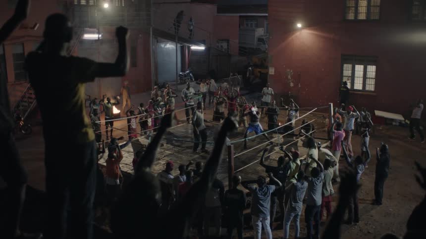 A crowd cheers at an outdoor boxing match