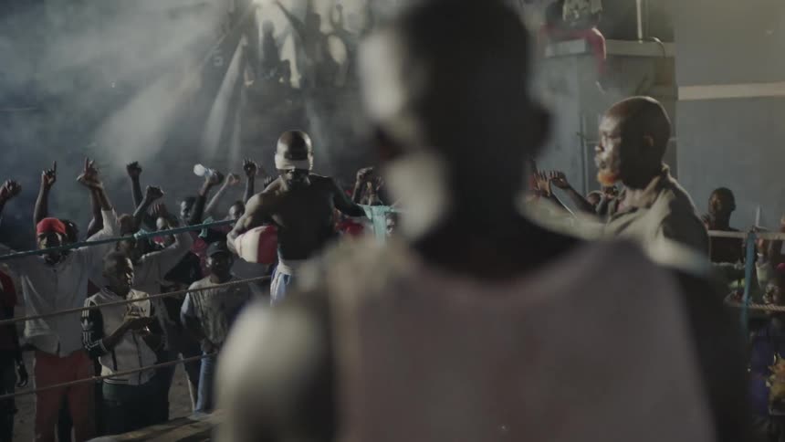 A crowd cheers at an outdoor boxing match