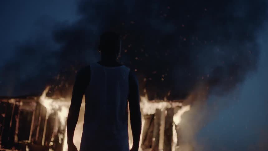 A man watches a house burn