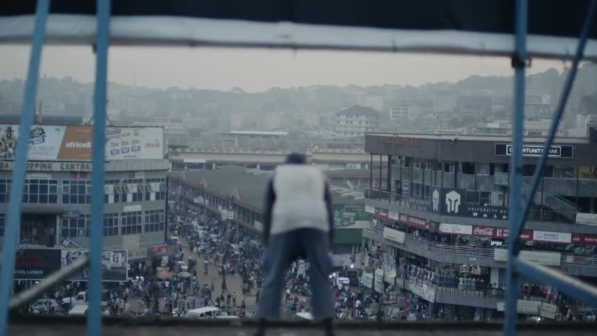 A man is leaning over and breathing heaving on a rooftop at dusk