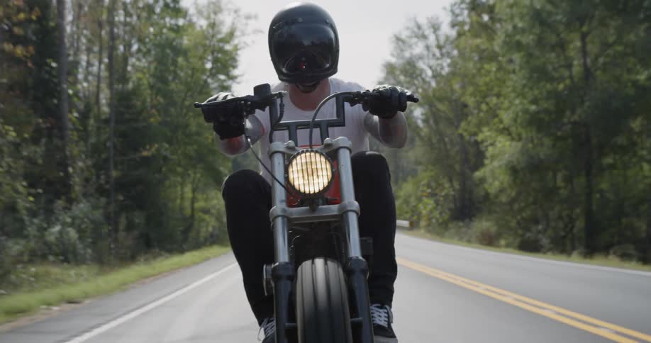 A motorcyclist rides on a rural road