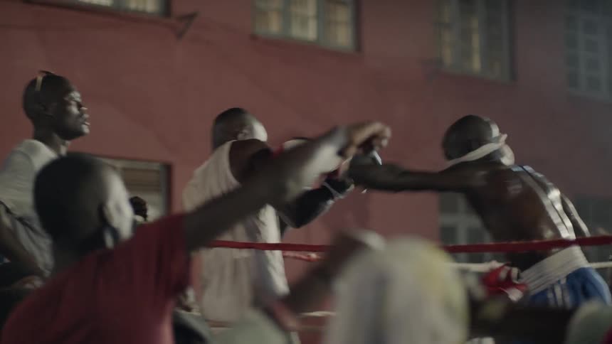 A crowd cheers at an outdoor boxing match