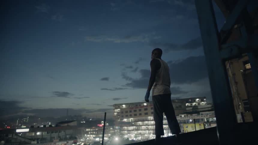 Man stands on a building rooftop at dusk