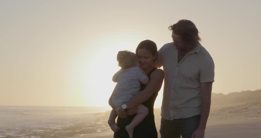 Man woman and child stand on the beach on a sunny day