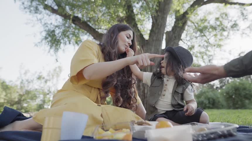 A playful mother touching child forehead while spending quality time during picnic.