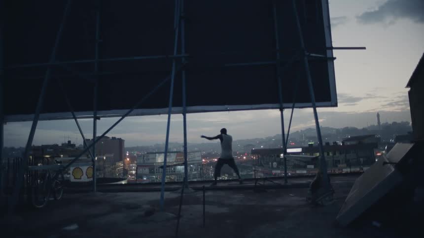 A boxer punches the air on a city rooftop