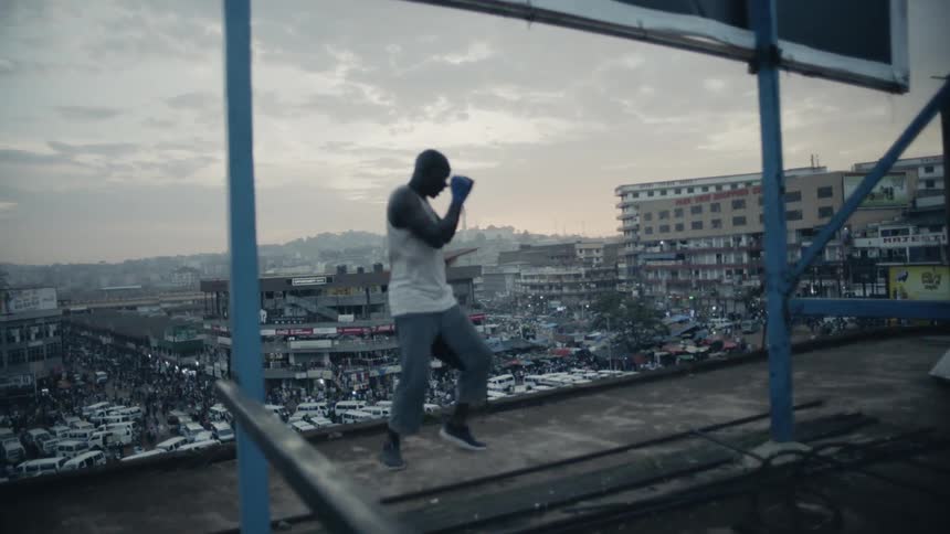 A boxer punches the air on a building rooftop
