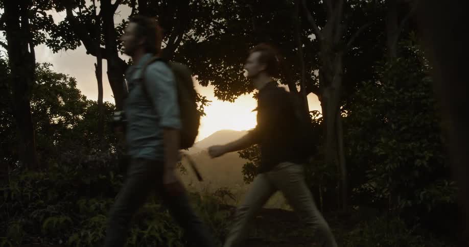 Two men are hiking in a natural landscape at sunset