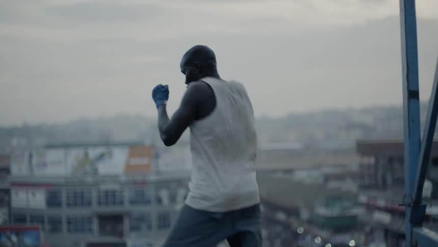 Man is practicing boxing punches on rooftop in city