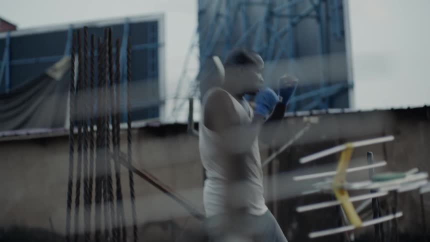 Man practices punching while standing on a rooftop