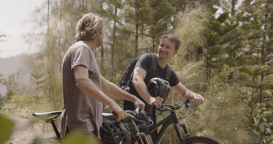 Two men are standing and talking with mountain bikes in wilderness