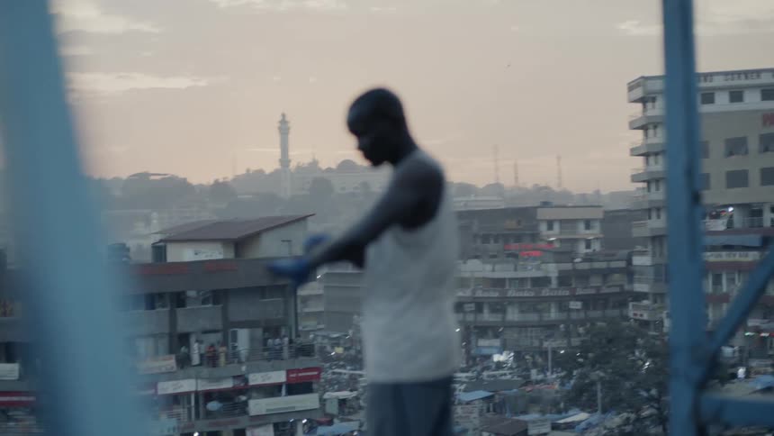 Man stands on a rooftop overlooking a city below wrapping his wrists