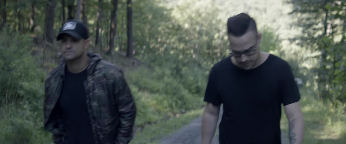 Two men walk in the woods on a sunny day