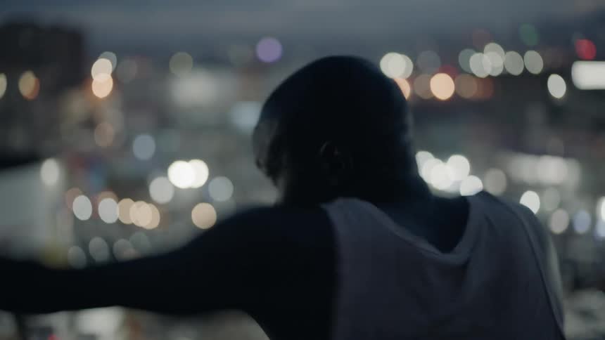A boxer punches the air on a building rooftop