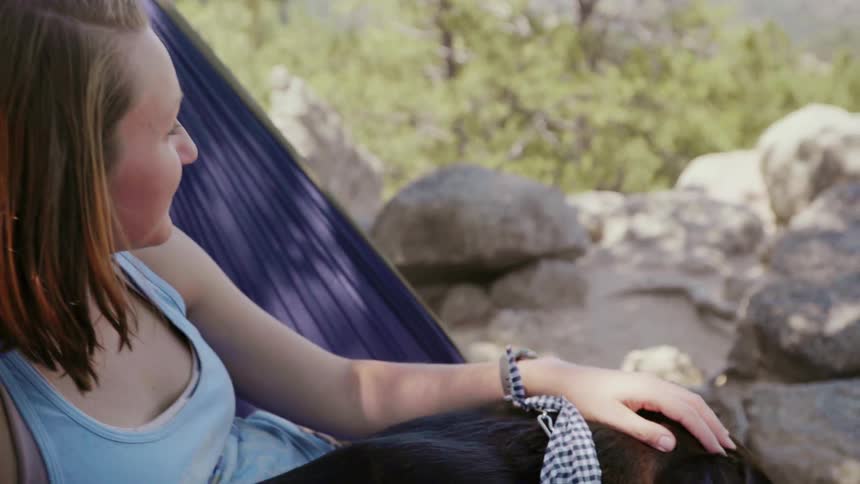 A woman and dog swing in a hammock