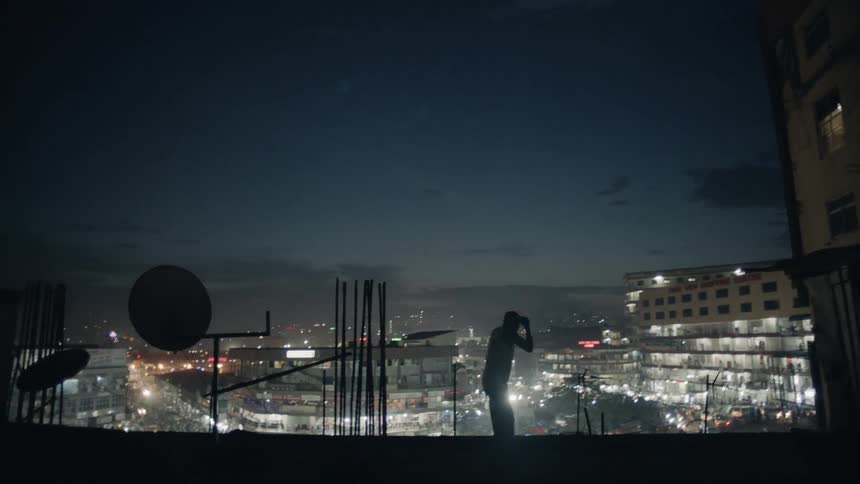 Man is practicing boxing punches on city rooftop at night