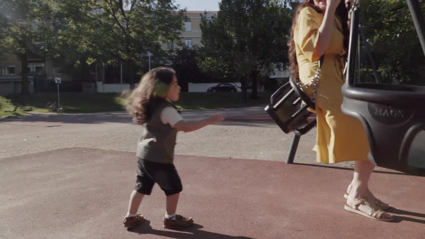 A woman and young child play on swings in a park