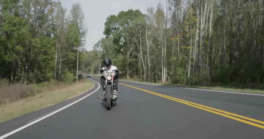 A motorcyclist rides on a rural road