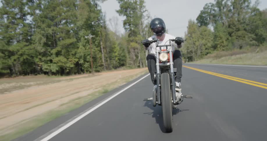 Man rides a motorcycle down a country road