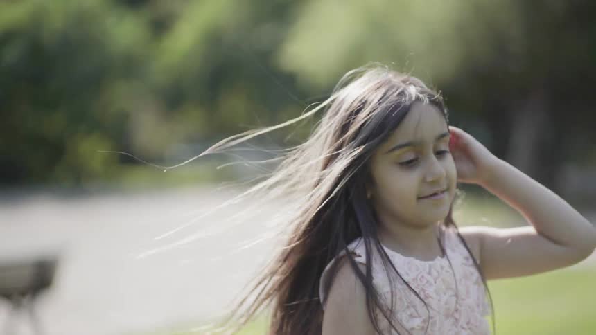 A girl spins on a grassy lawn