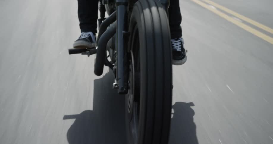 A man is riding a motorcycle on a rural road in daylight