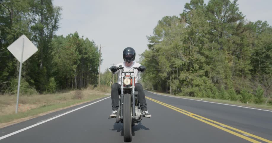 A man motorcycles on a rural road