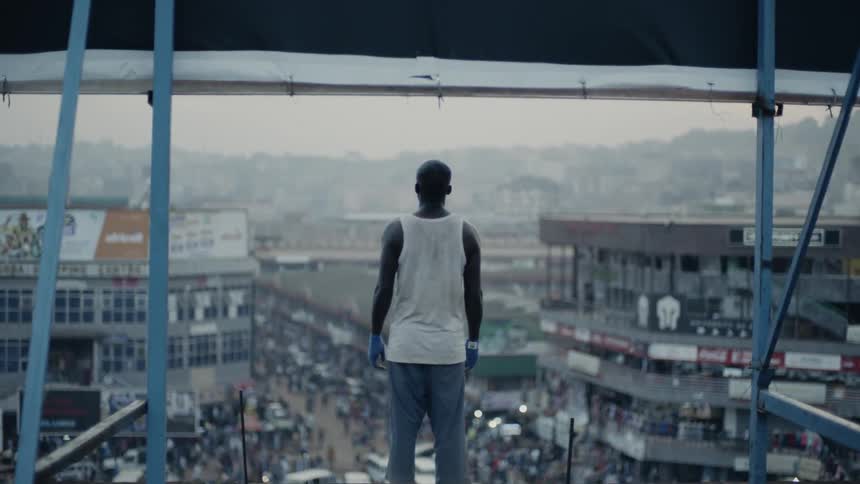 Man stands on a rooftop looking at the crowded city street below