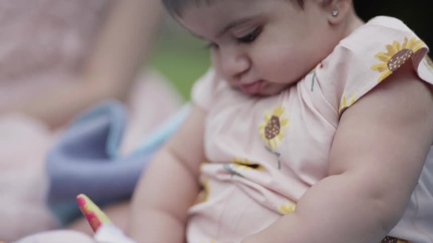 Child plays with toys sitting on a blanket outside
