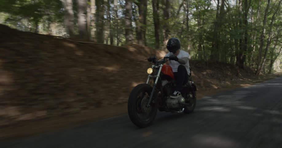 Man is riding motorcycle on road surrounded by trees