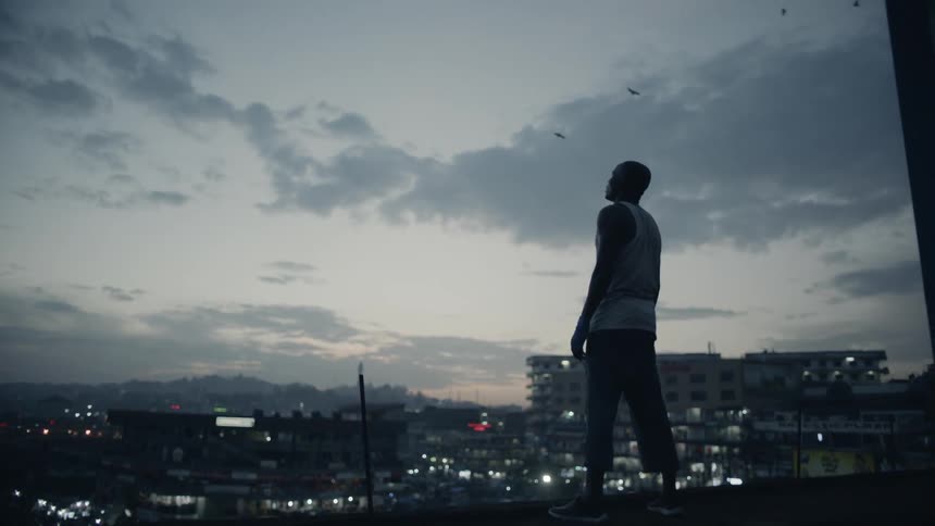 Man stands on a building rooftop at dusk