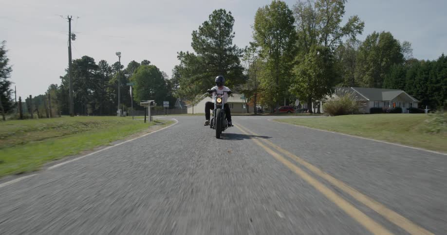 A man motorcycles on a rural road
