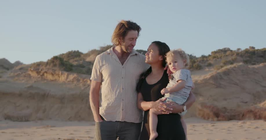 A young family stands on a beach