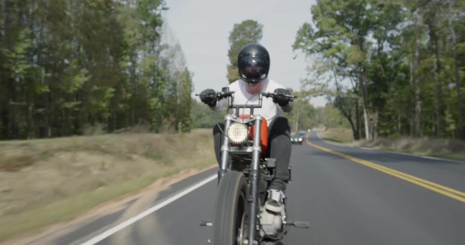 A motorcyclist rides on a rural road