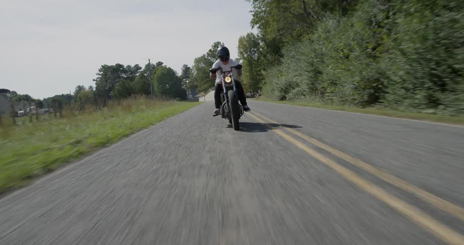 A motorcyclist rides on a rural road