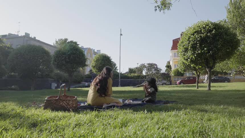 Woman and child sit on a blanket and have a picnic in the park