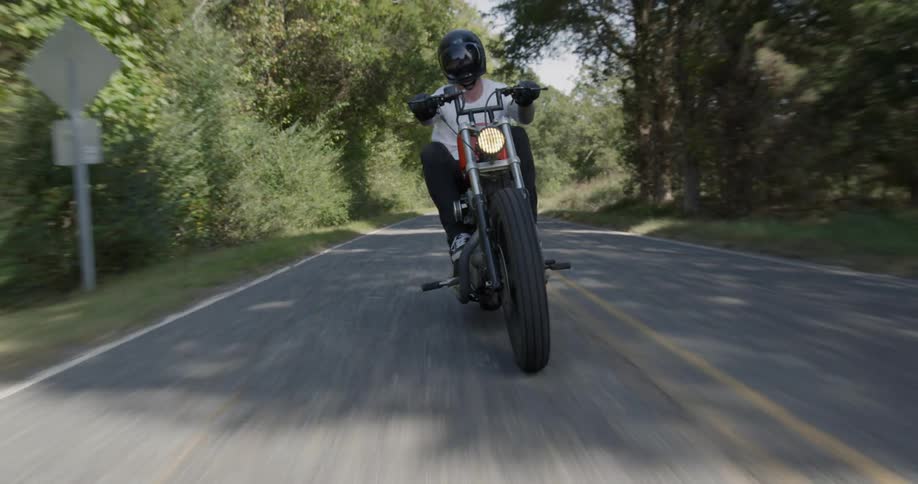 A motorcyclist rides on a rural road