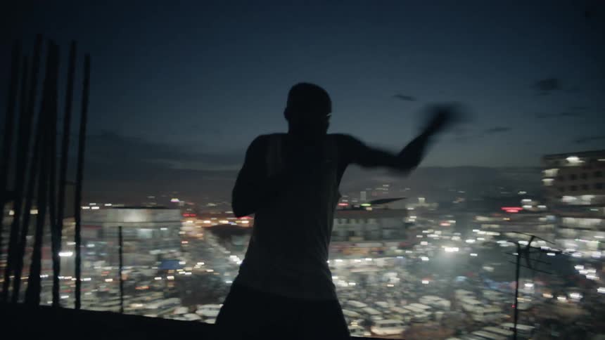 A boxer punches the air on a building rooftop