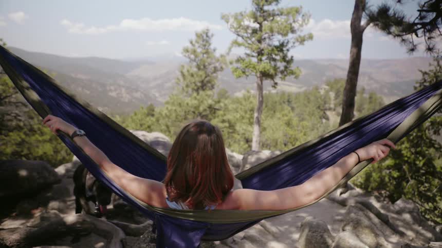 Woman swings in a hammock in mountains