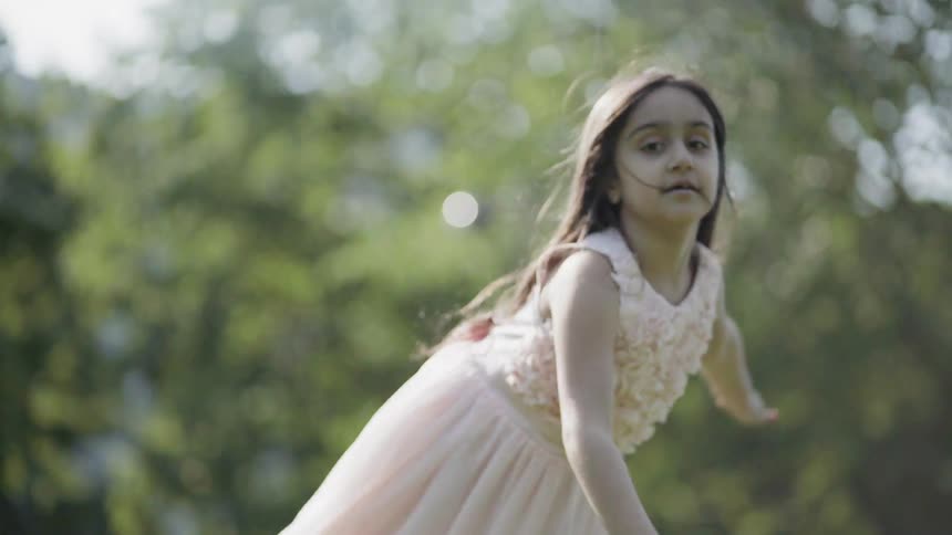 A girl plays on a grassy lawn