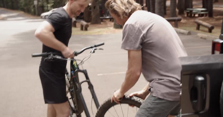 Man puts a tire on a bicycle in a parking lot