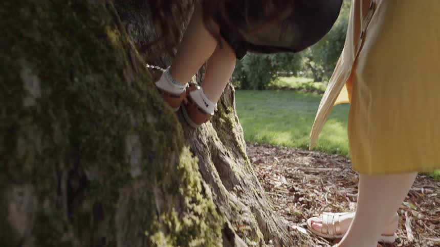 Woman helps a young child climb a tree