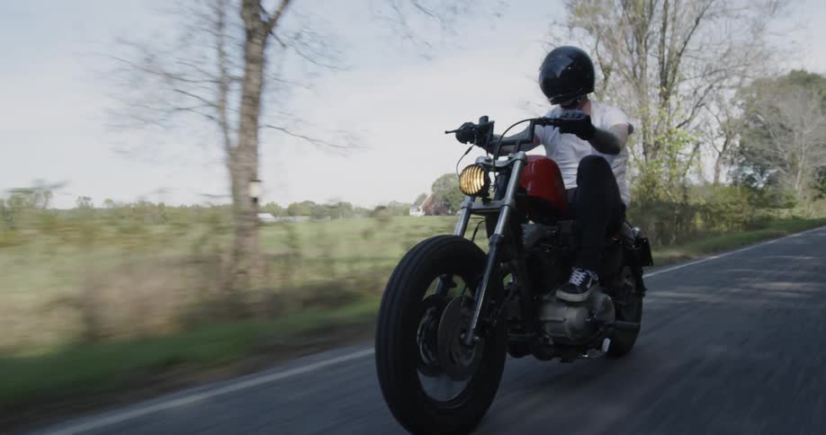 Man drives a motorcycle down a country road