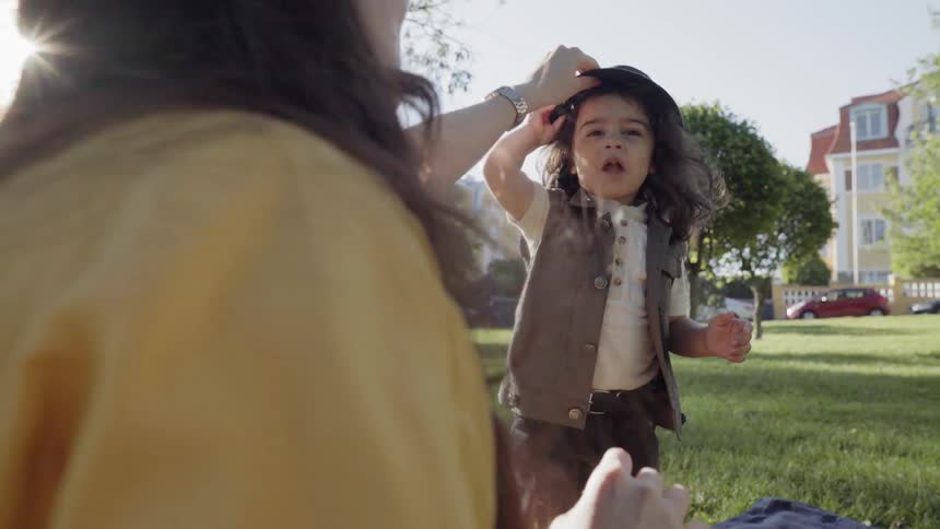 A mother fixing her child's hair during a family picnic in park.