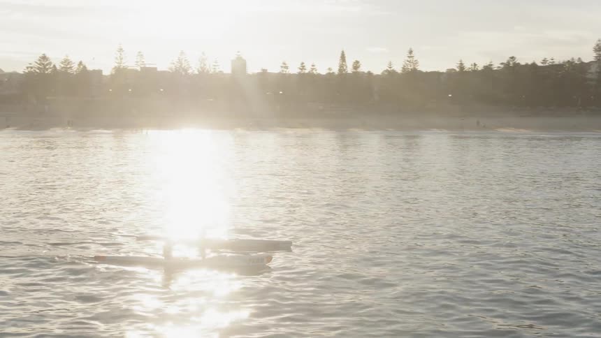 Two canoes travel over the rough water