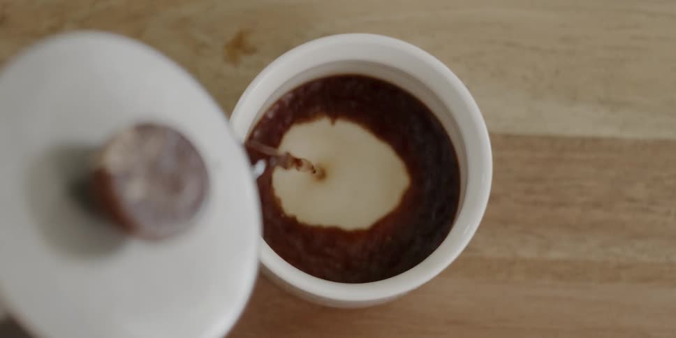 Tea is being poured into a cup on a table in daylight