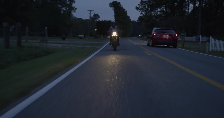 Person is riding motorcycle on neighborhood street at night